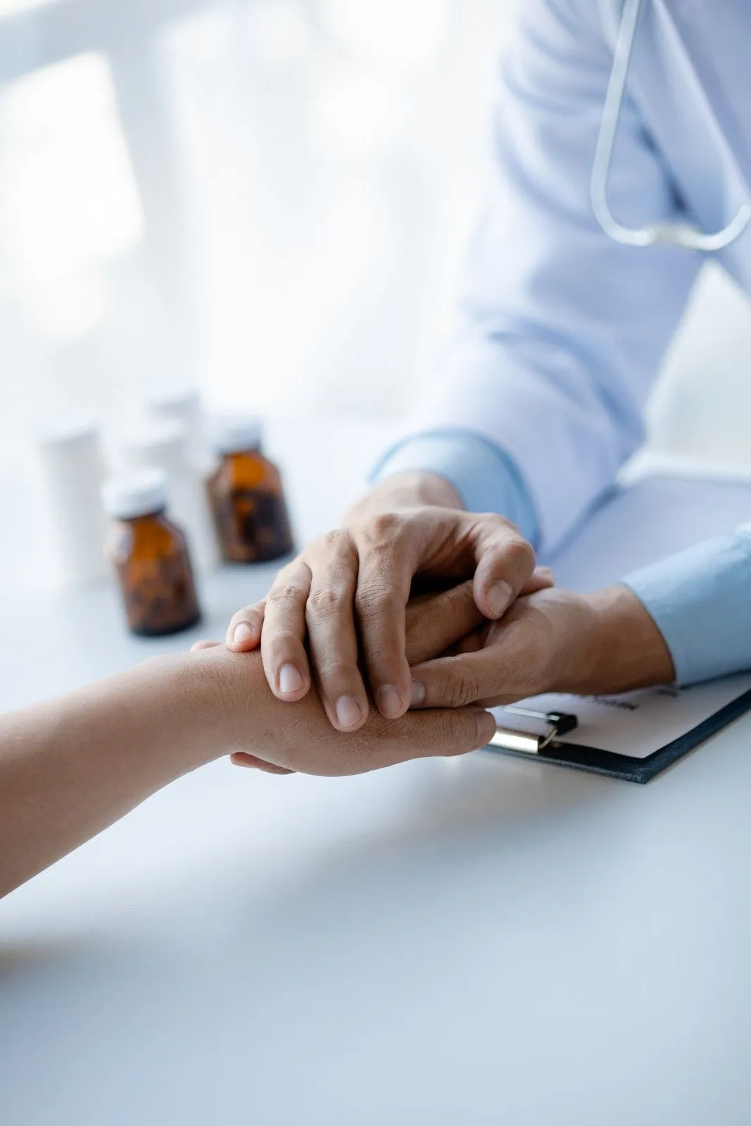 Care provider holding an older person's hand across a table
